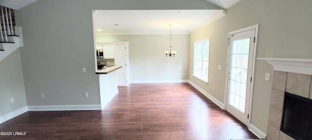 unfurnished living room featuring stairs, dark wood-style floors, a fireplace, and a chandelier