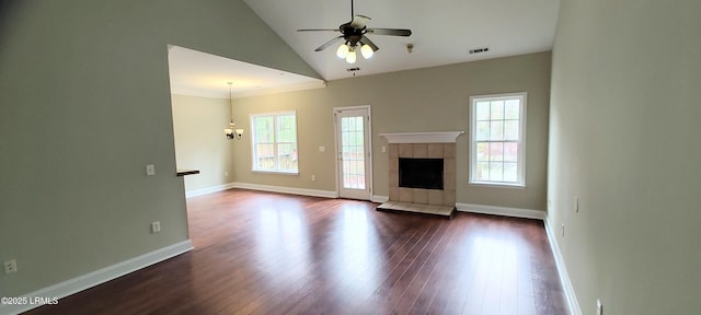 unfurnished living room with high vaulted ceiling, dark wood-type flooring, ceiling fan with notable chandelier, baseboards, and a tile fireplace