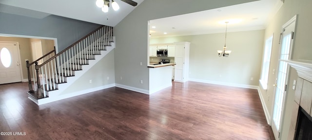 unfurnished living room with a wealth of natural light, dark wood-type flooring, and stairs