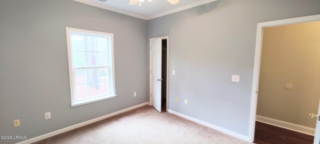 carpeted empty room with crown molding, baseboards, and ceiling fan