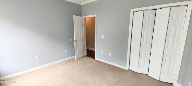 unfurnished bedroom featuring light carpet, baseboards, and a closet