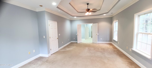 unfurnished room with a tray ceiling, baseboards, a healthy amount of sunlight, and crown molding