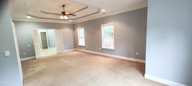 spare room featuring baseboards, a raised ceiling, light carpet, and crown molding