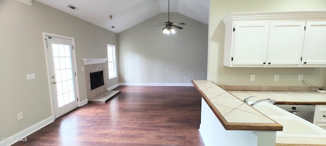 kitchen featuring a wealth of natural light, dark wood-style floors, tile counters, and a tiled fireplace