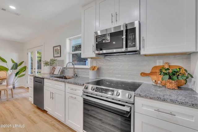 3001 N St, Beaufort, SC 29902 - kitchen with stainless steel appliances, a sink, light wood finished floors, white cabinets, and light stone counters