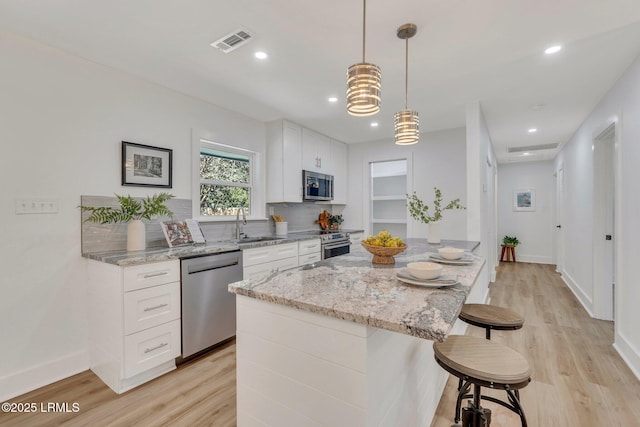 3001 N St, Beaufort, SC 29902 - kitchen featuring stainless steel appliances, light wood-type flooring, a kitchen breakfast bar, a center island, and white cabinetry