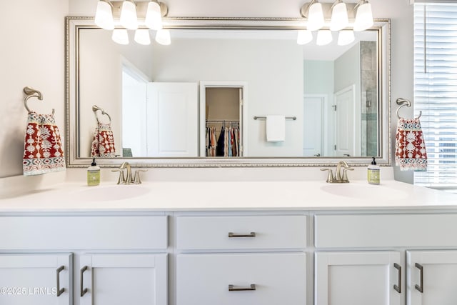 bathroom featuring a sink, a walk in closet, an inviting chandelier, and double vanity