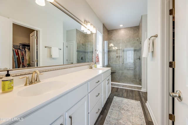full bathroom featuring wood finished floors, a sink, a walk in closet, and a stall shower