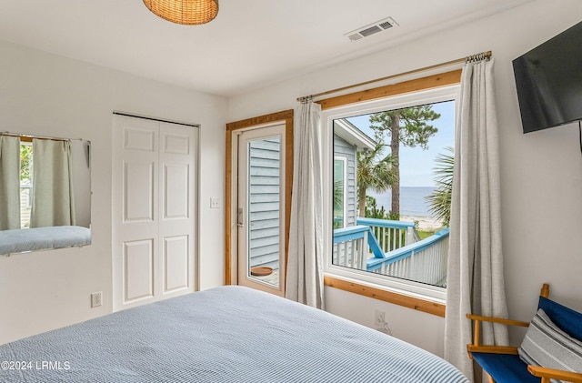 bedroom featuring multiple windows, a water view, and a closet