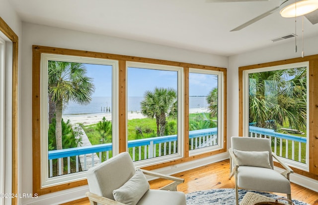 sunroom featuring ceiling fan and a water view