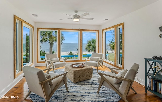 sunroom / solarium featuring ceiling fan and a water view