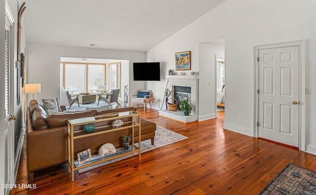 living room with wood-type flooring, lofted ceiling, and a fireplace