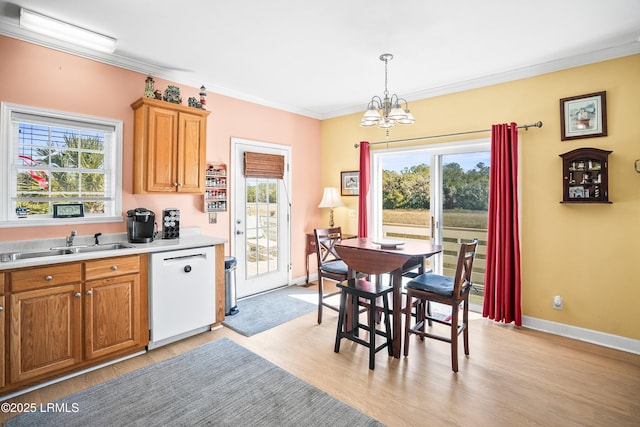 kitchen with a wealth of natural light, light countertops, ornamental molding, white dishwasher, and a sink