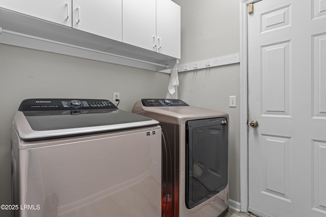 clothes washing area featuring independent washer and dryer and cabinets