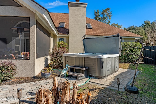 rear view of property with a hot tub and a patio