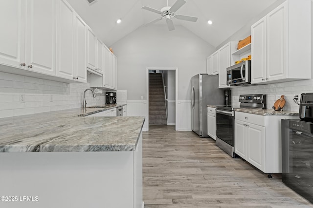 kitchen with appliances with stainless steel finishes, high vaulted ceiling, light stone counters, white cabinets, and beverage cooler