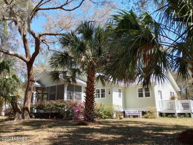 view of property exterior with a sunroom and a wooden deck