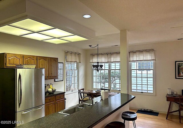 144 Locust Fence Rd, Saint Helena Island, SC 29920 - kitchen featuring a sink, dark countertops, freestanding refrigerator, an inviting chandelier, and a breakfast bar area
