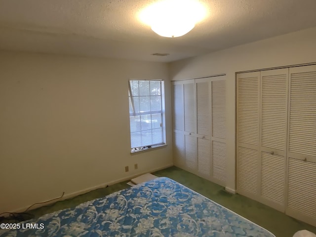 unfurnished bedroom featuring multiple closets and a textured ceiling