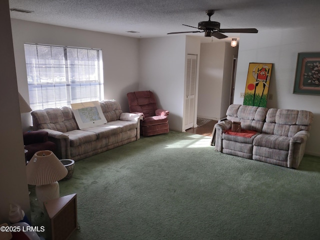 carpeted living room with ceiling fan and a textured ceiling