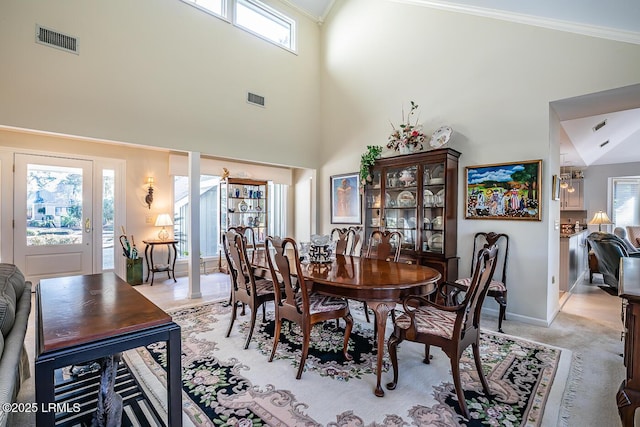 dining room with crown molding, a towering ceiling, and light carpet