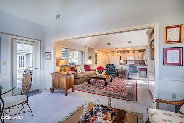 living room featuring high vaulted ceiling and light hardwood / wood-style floors