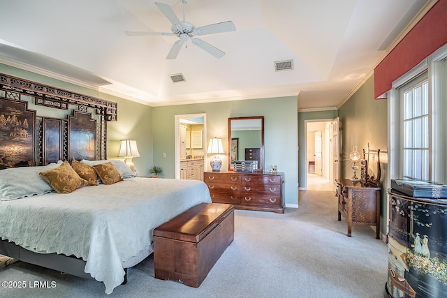 bedroom with ensuite bath, ceiling fan, a tray ceiling, ornamental molding, and light colored carpet