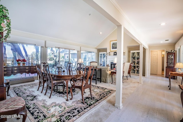 dining room with crown molding, vaulted ceiling, and light wood-type flooring