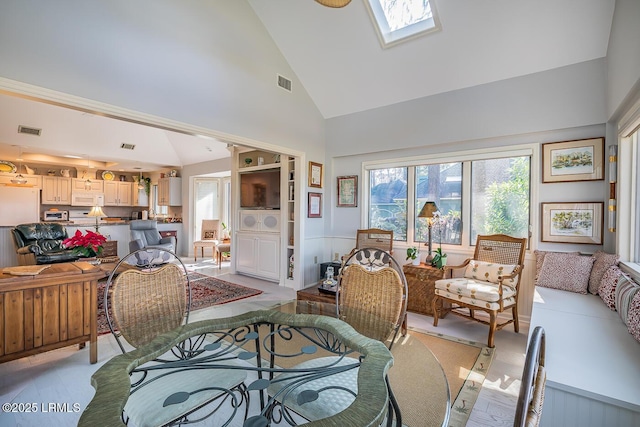 dining space featuring a skylight and high vaulted ceiling