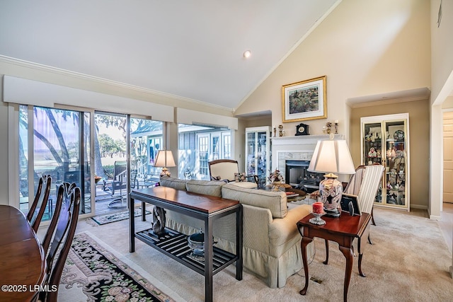 living room featuring high vaulted ceiling, ornamental molding, a high end fireplace, and light carpet