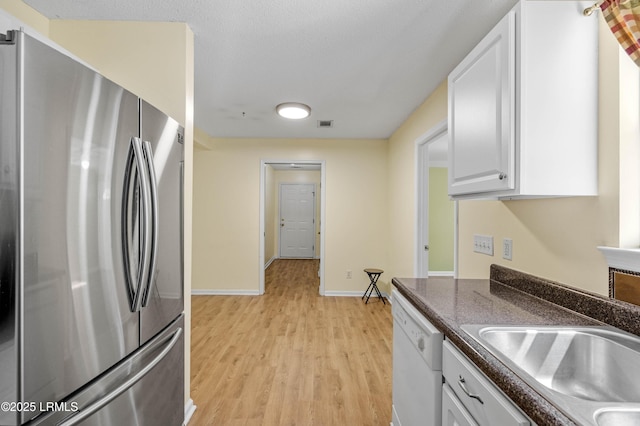 16 Star Magnolia Ct, Beaufort, SC 29907 - kitchen featuring freestanding refrigerator, white dishwasher, dark countertops, light wood finished floors, and white cabinetry