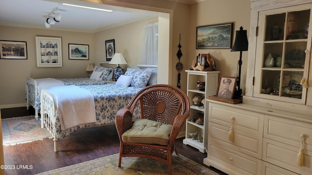 bedroom with dark hardwood / wood-style flooring, track lighting, and ornamental molding