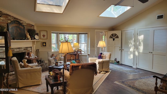 living room with hardwood / wood-style flooring, ornamental molding, a fireplace, and vaulted ceiling with skylight