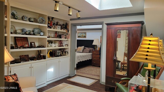 interior space with crown molding, a skylight, dark hardwood / wood-style floors, and track lighting