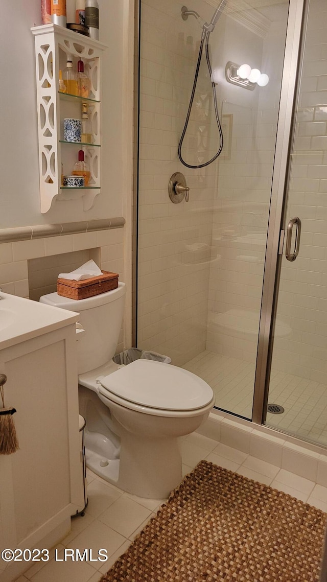 bathroom with tile walls, tile patterned flooring, vanity, walk in shower, and toilet