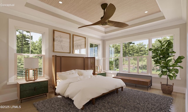 bedroom with a tray ceiling, wood finished floors, baseboards, and ornamental molding