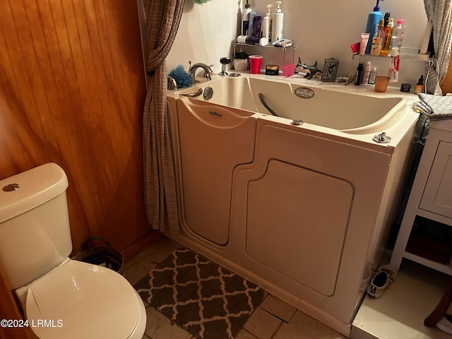 bathroom featuring tile patterned floors, toilet, a bathing tub, and washer / clothes dryer