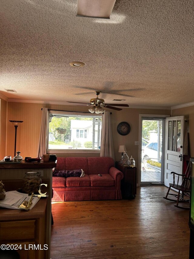 living room with dark hardwood / wood-style flooring, ceiling fan, ornamental molding, and a healthy amount of sunlight