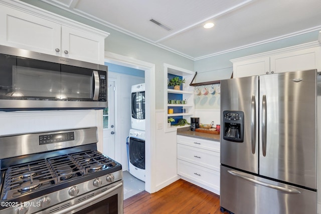 kitchen featuring stacked washing maching and dryer, stainless steel appliances, visible vents, white cabinets, and dark wood-style flooring