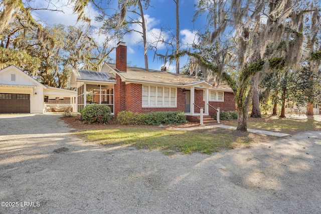 view of front facade with driveway, a chimney, a garage, and brick siding