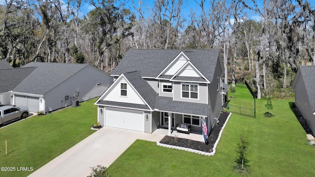 traditional-style home with a front yard, a patio, fence, roof with shingles, and concrete driveway