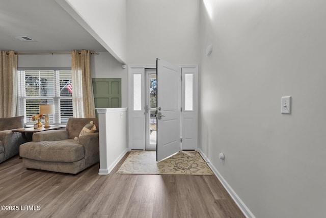 foyer featuring a wealth of natural light, visible vents, baseboards, and wood finished floors