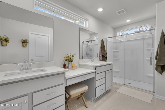 full bath with visible vents, two vanities, a stall shower, tile patterned floors, and a sink