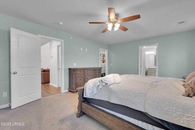 carpeted bedroom featuring visible vents, ceiling fan, ensuite bath, and baseboards