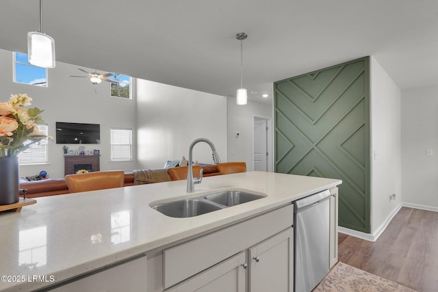 kitchen with a brick fireplace, open floor plan, dishwasher, white cabinetry, and a sink