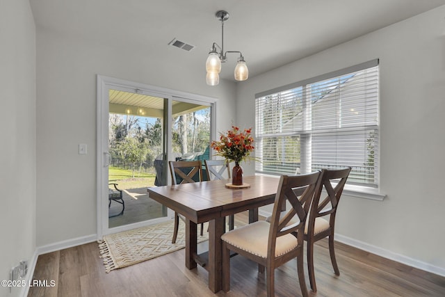 dining area with visible vents, baseboards, an inviting chandelier, and wood finished floors