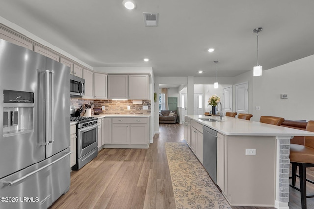 kitchen with visible vents, a breakfast bar, light wood-style flooring, a sink, and stainless steel appliances