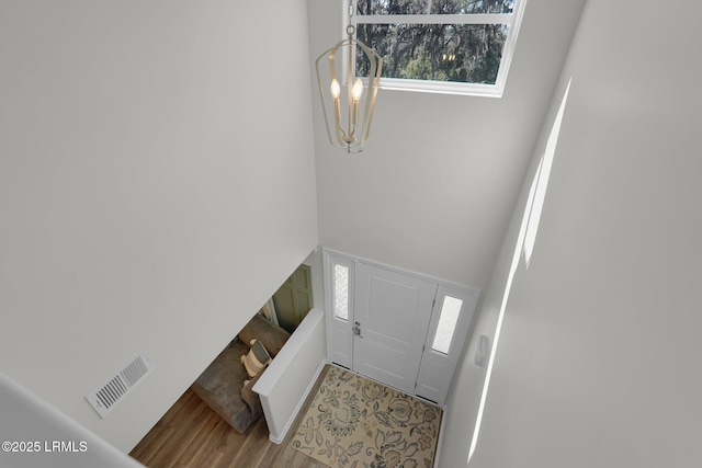 entrance foyer featuring a chandelier, visible vents, a high ceiling, and wood finished floors