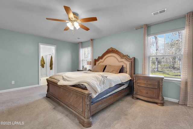 bedroom with visible vents, baseboards, ceiling fan, ensuite bathroom, and light colored carpet