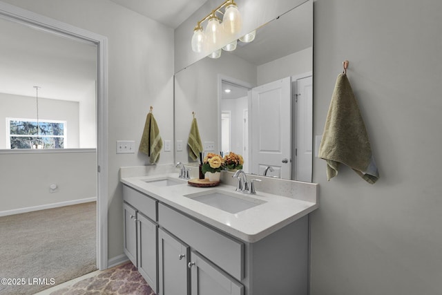 bathroom with an inviting chandelier, double vanity, baseboards, and a sink